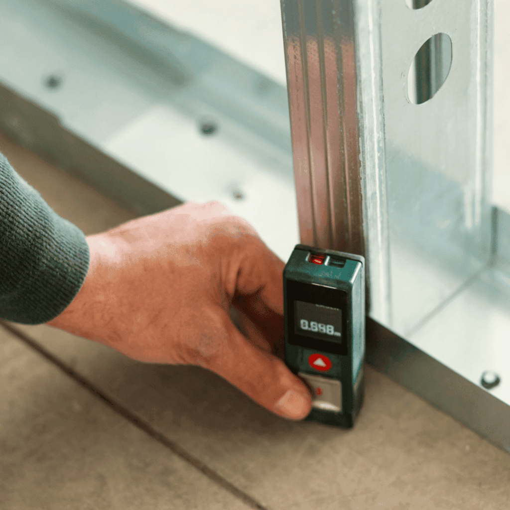 Main d'un diagnostiqueur utilisant un télémètre laser pour mesurer une surface, diagnostic Loi Carrez.